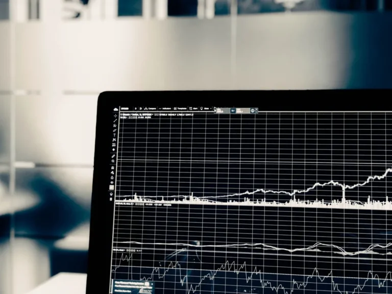 Close-up of a computer screen displaying financial graphs and data charts on a grid background, perfect for illustrating concepts in an Intro to Big Data course.