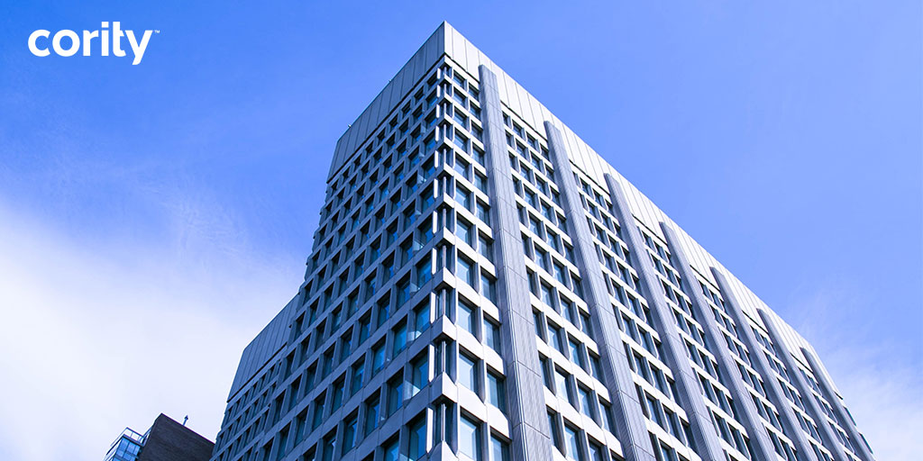 Tall modern office building with many windows against a blue sky; Cority EHS software logo in the top left corner reflects innovation backed by independent research.