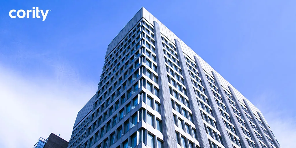 Tall modern office building with many windows against a blue sky; Cority EHS software logo in the top left corner reflects innovation backed by independent research.