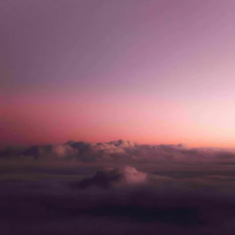 A serene view of soft clouds seen from above, bathed in gentle pink and purple hues during a peaceful sunrise or sunset, with a calming gradient sky overhead—an atmosphere as tranquil as Greenstone.