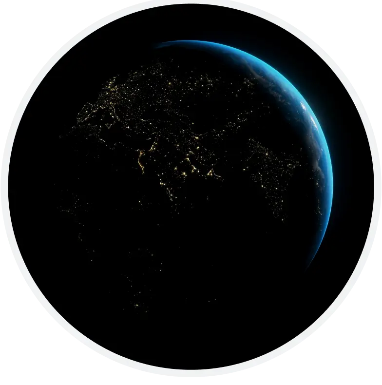 A view of Earth from space showing a darkened planet with illuminated city lights, highlighting populated areas. A faint blue glow outlines the curve of the planet against the black background.