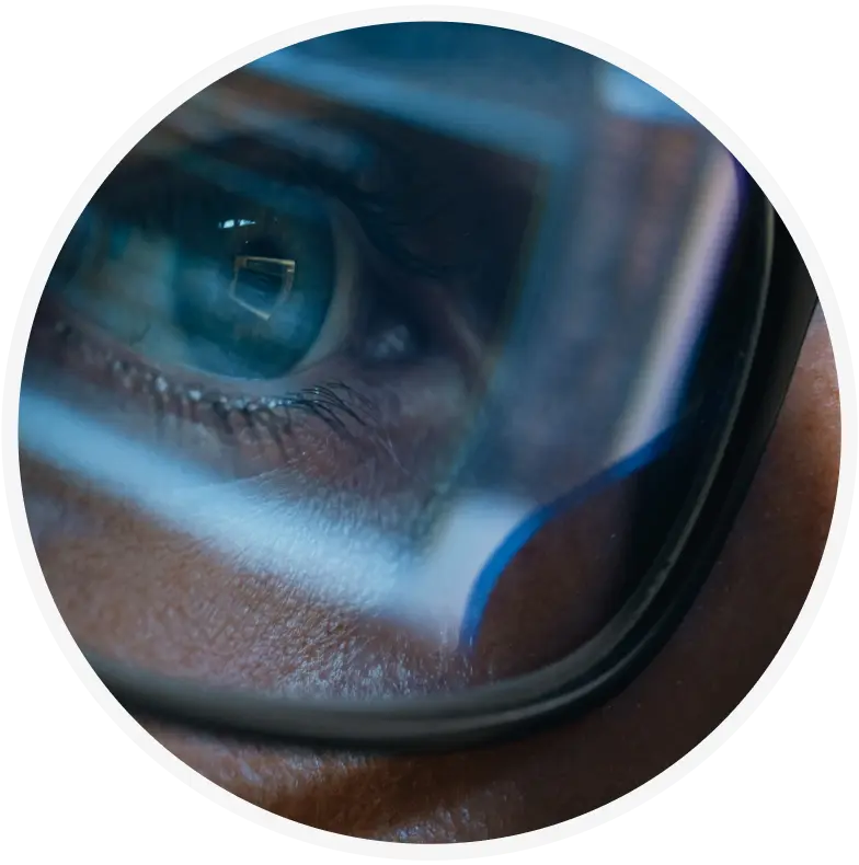 A close-up of a persons eye wearing glasses, with a computer screen reflected in the lens, suggesting focus and concentration on digital work.