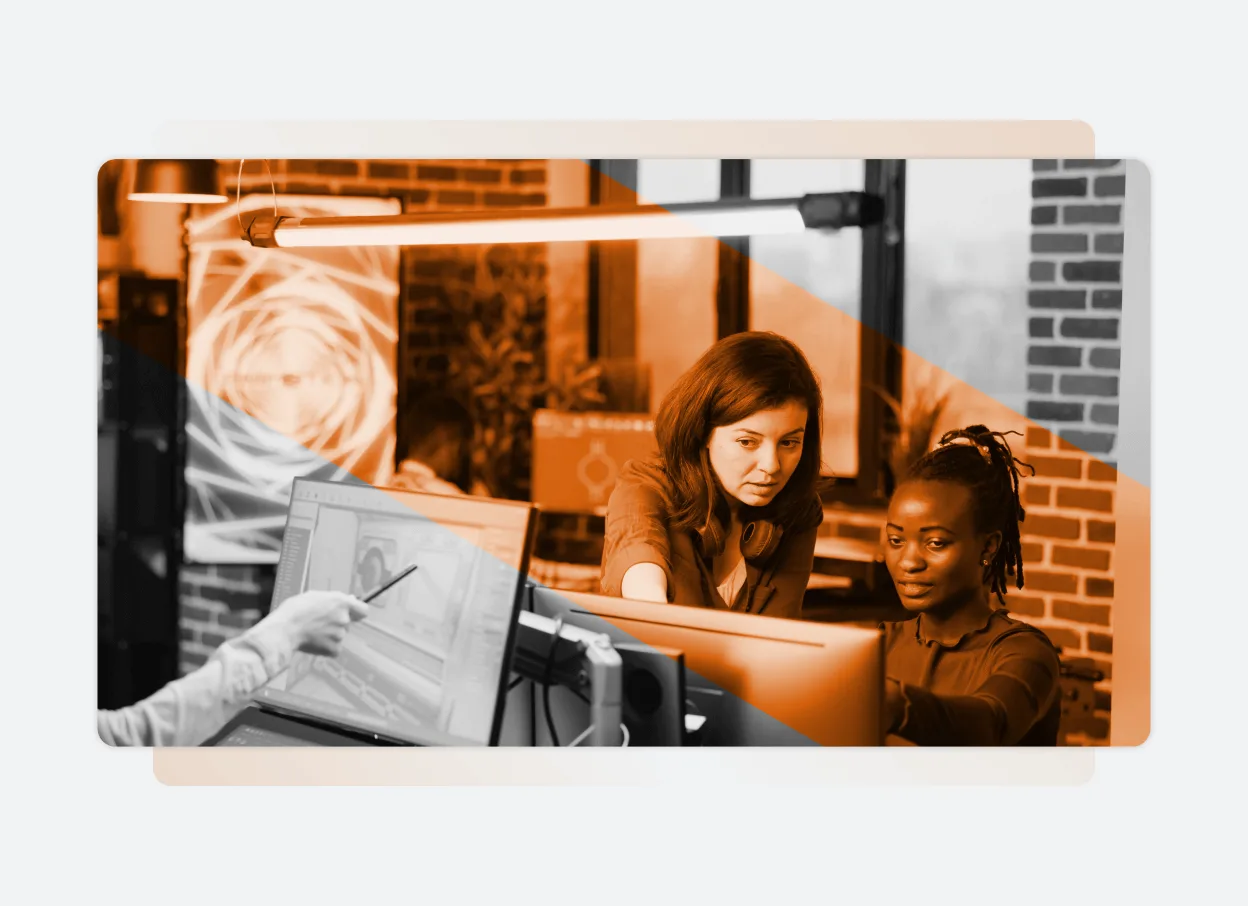 Three people collaborate at computer monitors in a modern office with brick walls; one person points at a screen, while two others focus intently. The image, with an orange overlay effect, highlights teamwork powered by one seamless Solutions Platform.
