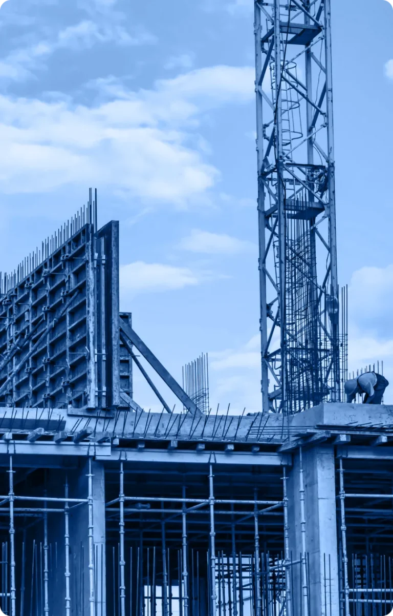 A construction site with steel framework, scaffolding, and a tower crane showcases the dynamic industry under a blue sky with scattered clouds.