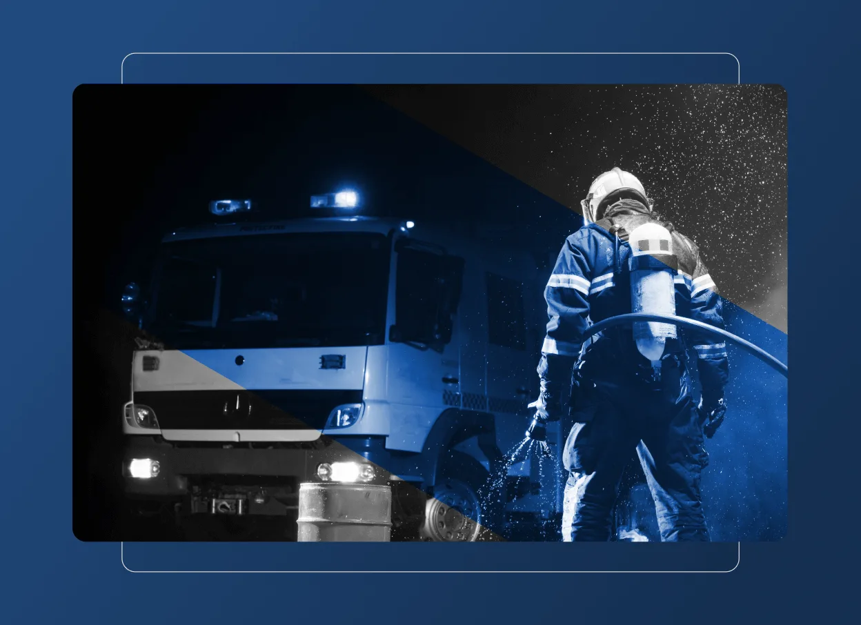 A firefighter in full gear stands facing a fire truck with flashing lights at night. The image, reminiscent of an accordion section, is split diagonally—half in blue tones and half in black and white.
