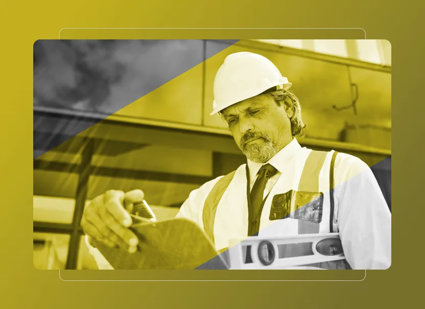 A male construction worker wearing a hard hat and safety vest reviews documents on a clipboard in front of a modern building, with a yellow overlay, surveying equipment in the foreground, and Safety Cloud technology ensuring site compliance.
