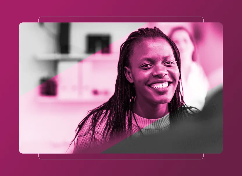 A woman with braided hair smiles warmly at someone off-camera. The image, tinted pink, features a blurred background and another person in soft focus—perfect for illustrating an Accordion Section on sustainability or the benefits of Sustainability Cloud.