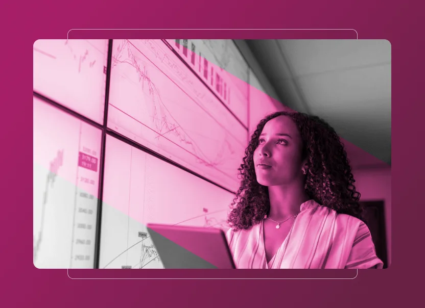 A woman with curly hair holds a laptop and looks thoughtfully at large display screens showing charts and graphs, highlighted by a pink overlay—perfect for illustrating data analysis in a Sustainability Cloud dashboard or an Accordion Section in presentations.
