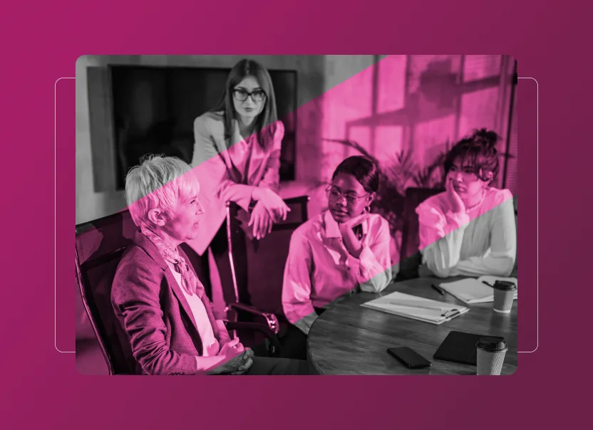 Four people sit and stand around a table during a meeting, discussing ideas, with Notebooks, a phone, and coffee cups on the table. A pink geometric overlay effect adds style—an ideal scene for exploring Sustainability Cloud or an Accordion Section feature.