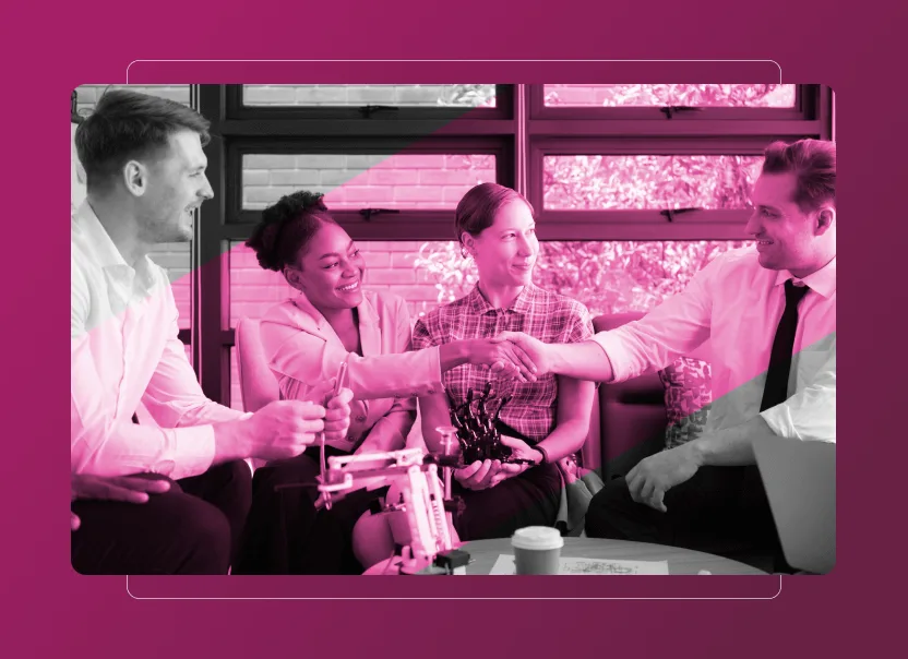 Four colleagues sit together, smiling and shaking hands in an office setting with a pink overlay; on the table are a robotic hand, coffee cup, and documents highlighting Sustainability Cloud initiatives.