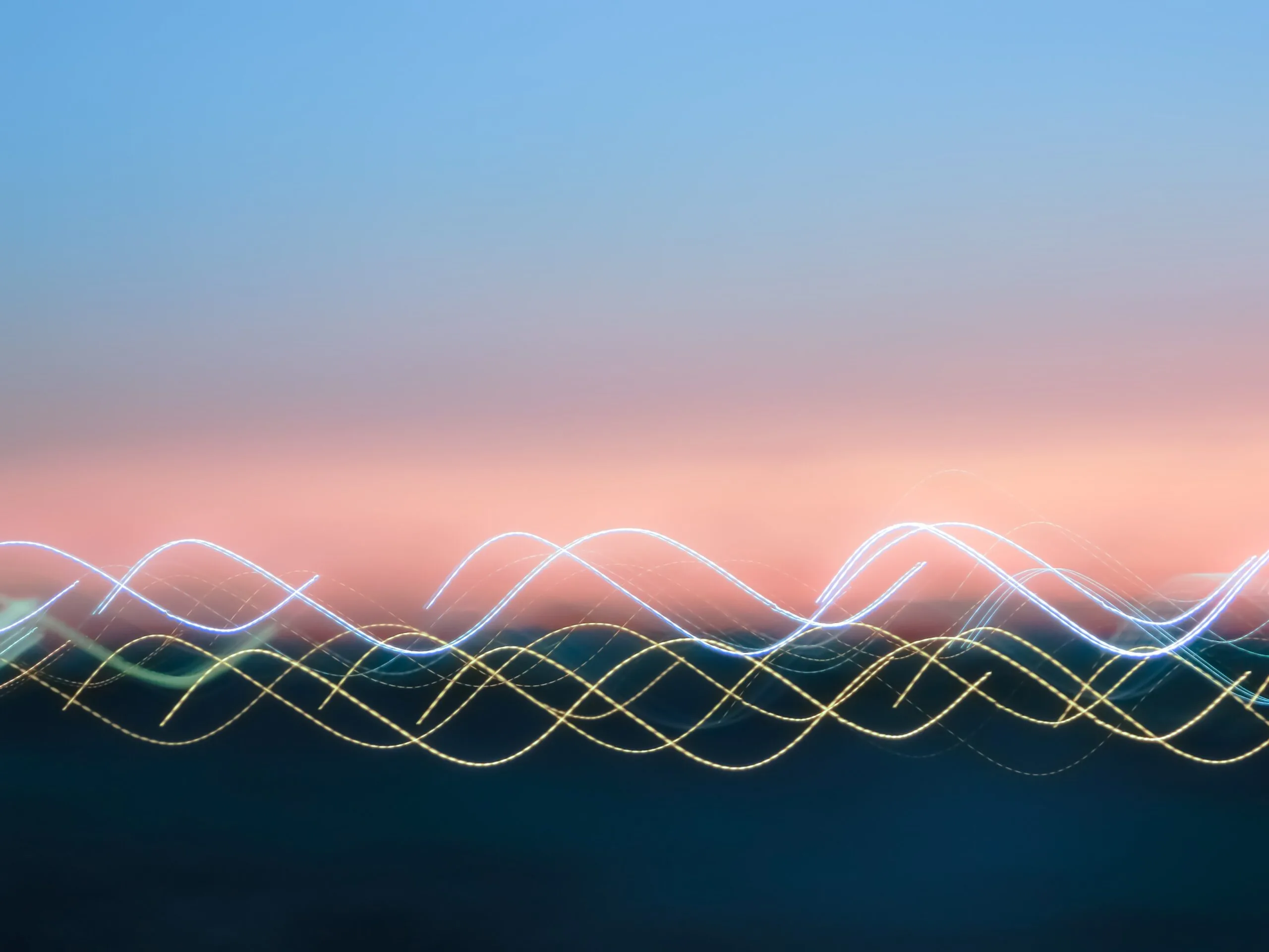 Abstract image of a sunset sky with a gradient of blue to pink and blurry, wavy lines of light in white, yellow, and blue across the bottom, resembling long-exposure photography.
