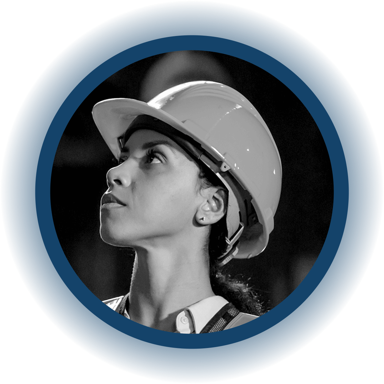 A woman wearing a hard hat and safety vest looks upward with a focused expression, set against a dark background and framed by a blue circular border, embodying the dedication seen in users of EHS software.